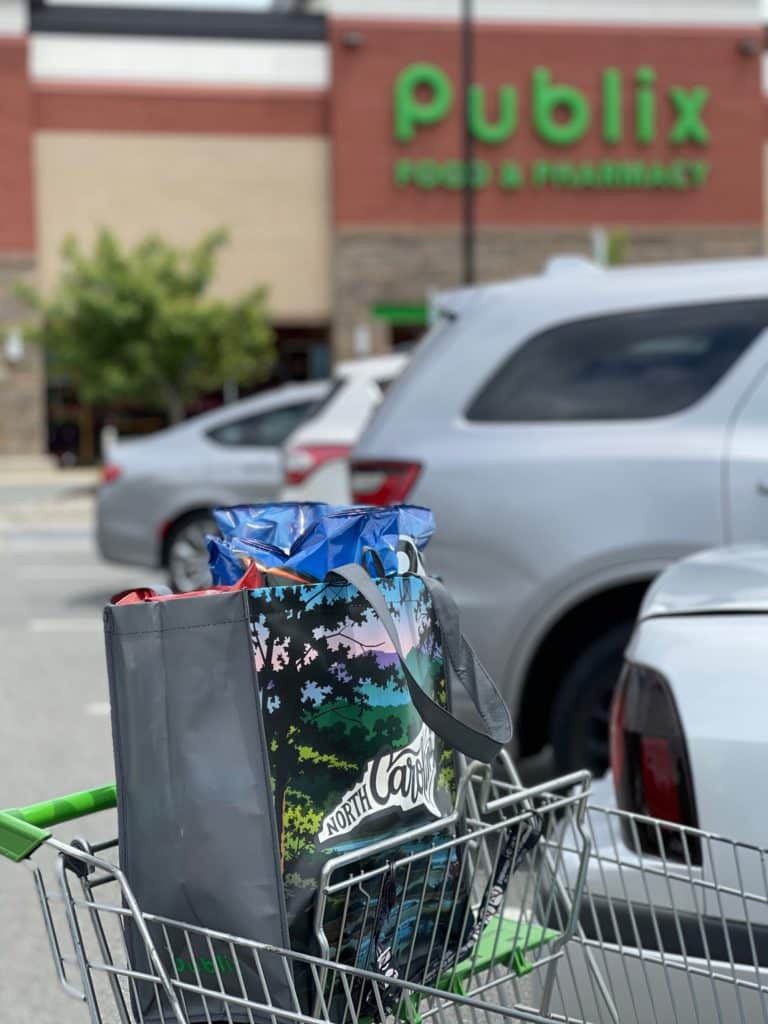 A shopping cart in front of Publix, with a reusable Publix bag full of Frito-Lay products.