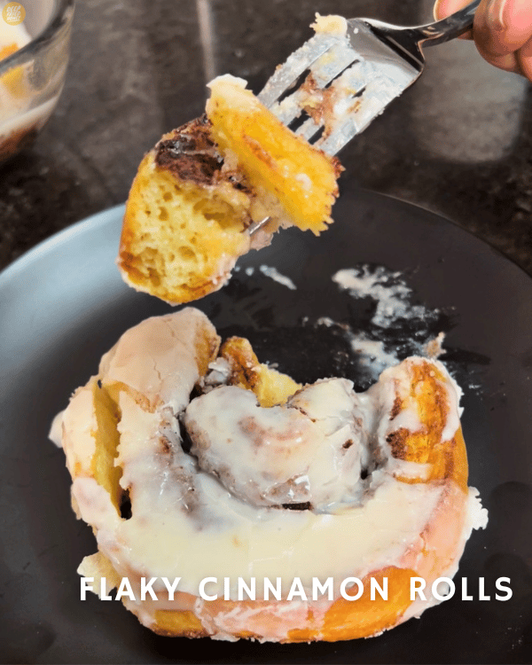 Flaky Cinnamon Rolls with cream cheese icing, partially eaten with a piece of cinnamon roll still on the fork
