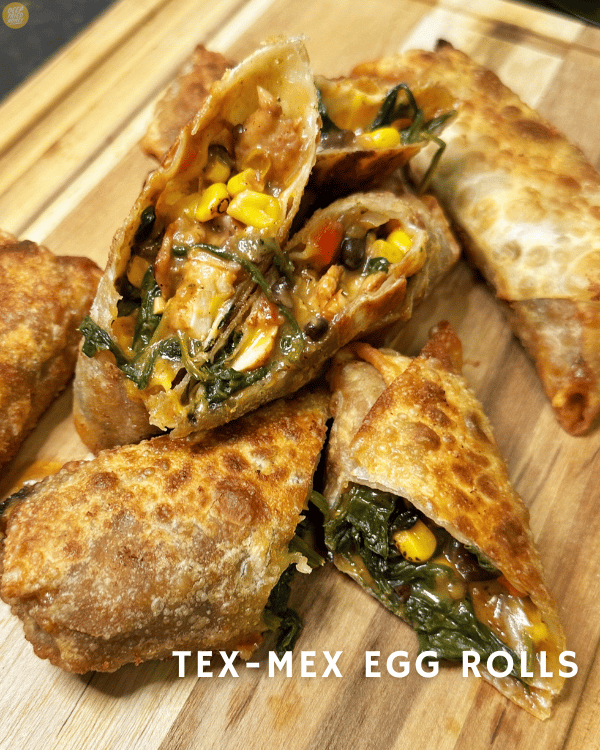 closeup of two Tex-Mex Egg Rolls cut open showing filling of chicken, cheese, corn, spinach, and black beans. 