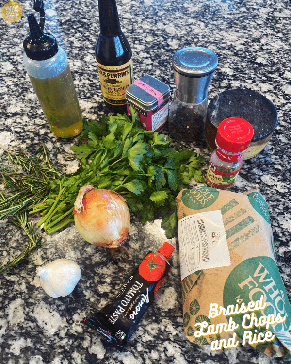 ingredients needed for Braised Lamb Chops and Rice including a bunch of parsley, an onion, a bulb of garlic, and lamb chops still wrapped in butcher paper